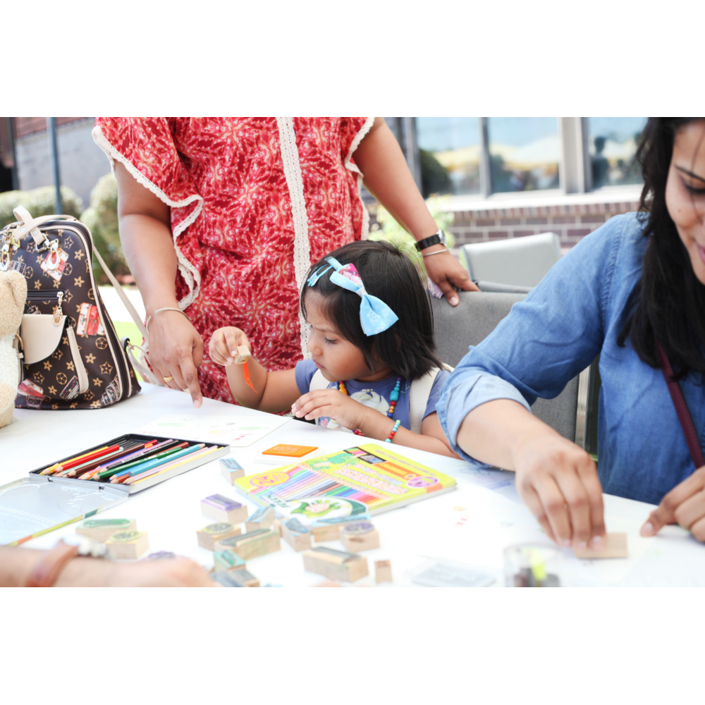 Little girl creating art with stamping blocks at LBMA's Family Artmaking