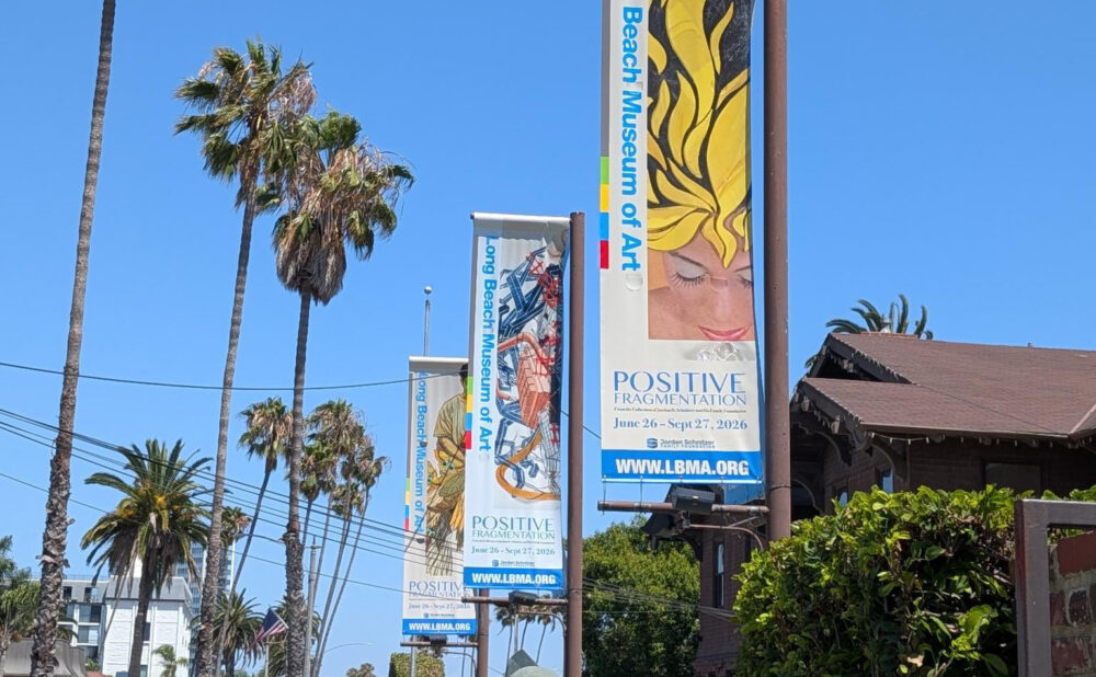 LBMA banners promoting Positive Fragmentation line the museum entrance beneath tall palm trees on a sunny day.